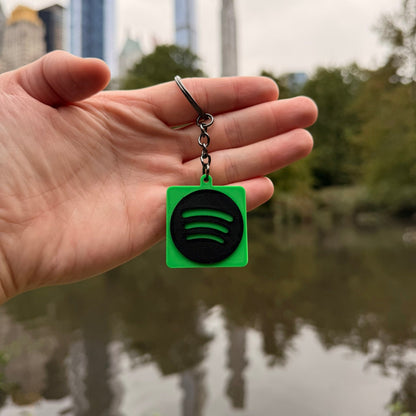 Hand holding a Spotify keychain with a cityscape in the background