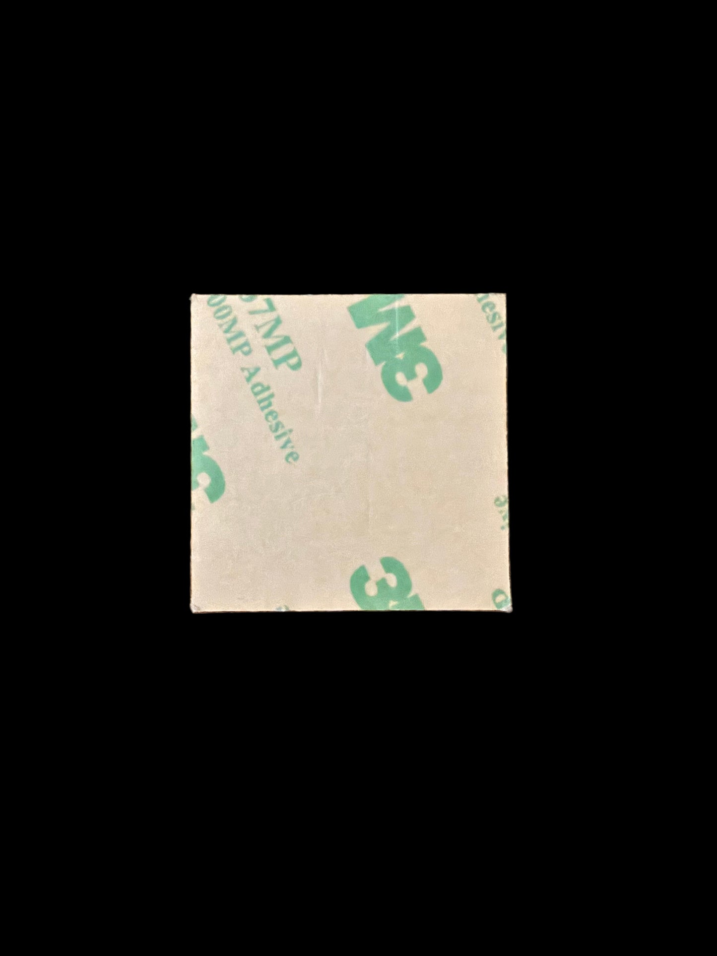 Square piece of tape with '3M' branding on a wooden surface